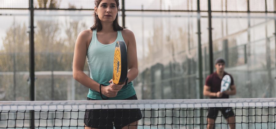 Padelspeler blokkeert een hard geslagen bal bij het net