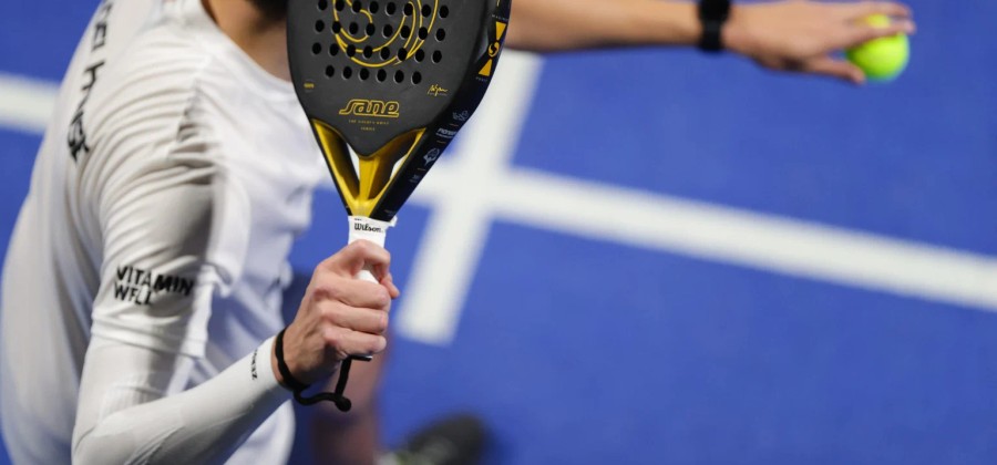 Padelspeler met witte overgrip om het handvat van zijn racket, klaar om te serveren