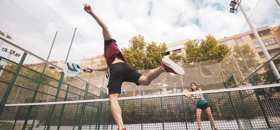 Padelspeler speelt een por tres, de bal verlaat het veld via de omheining