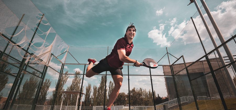 Padelspeler slaat een rulo met rollende armbeweging op de padelbaan