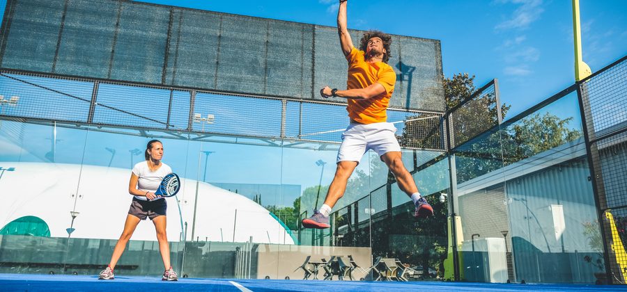Padelspeler slaat een krachtige overhead smash op de padelbaan